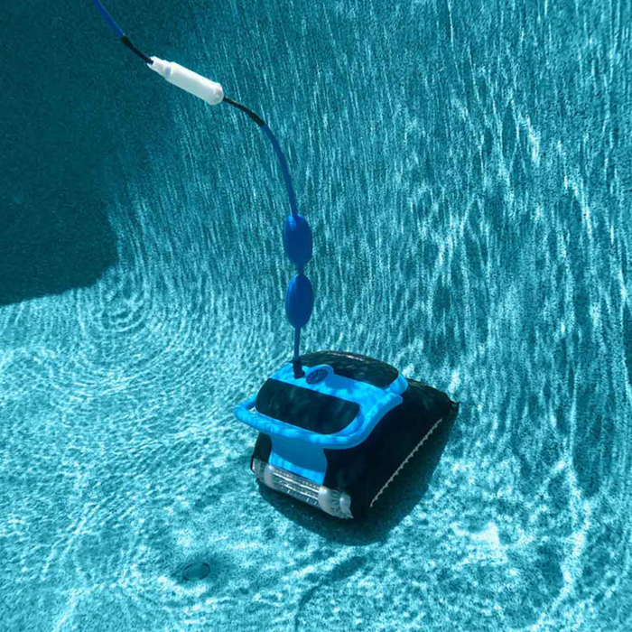 A Maytronics Dolphin Nautilus CC Plus Cleaner 99996406-PCI (with Wi-Fi) glides along the bottom of a clear, blue pool, effortlessly cleaning while connected by a cord. Control it with ease using the MyDolphin Plus app.