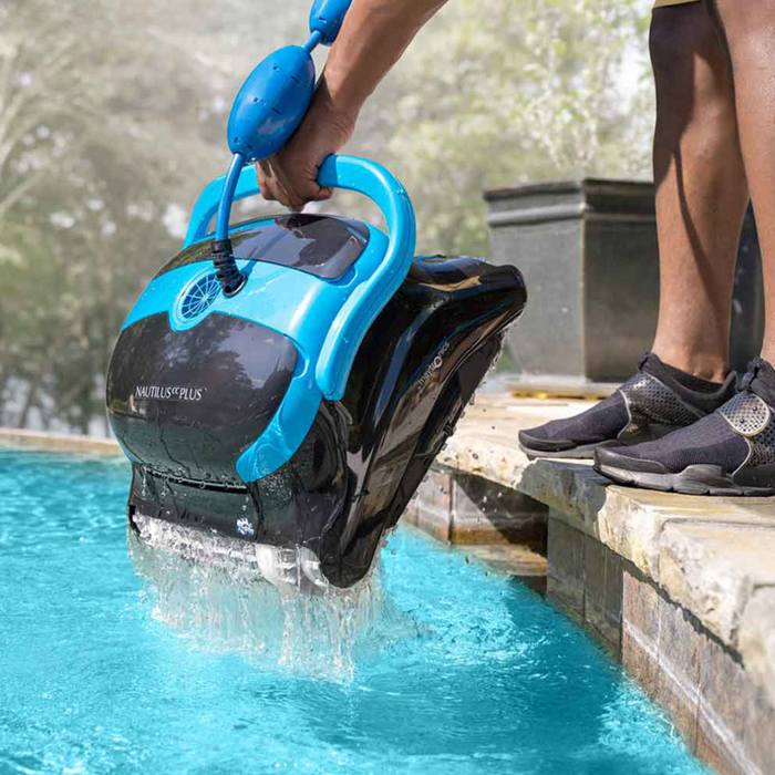 Person lifting a Maytronics Dolphin Nautilus CC Plus Cleaner 99996406-PCI (with Wi-Fi) out of the water by the handle, close to the pool's edge.