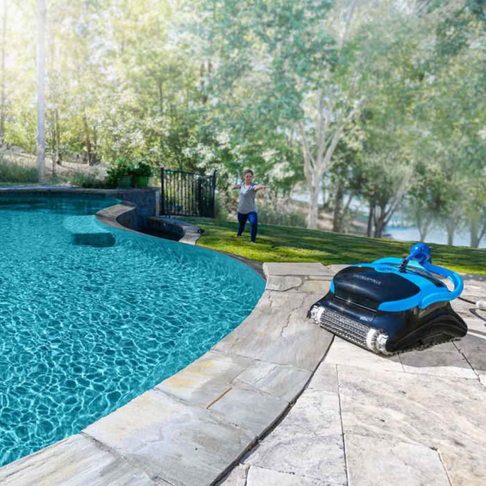 A child runs near a clear pool while a Maytronics Dolphin Nautilus CC Plus Cleaner 99996406-PCI (with Wi-Fi) operates on the edge of the patio, surrounded by trees.