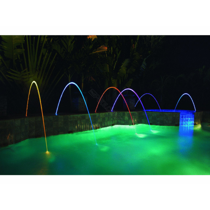Night pool with colorful Pentair 590021 Magicstream Laminar LED Light Engine with Body 100' Cord jets arching over green water, illuminated by IntelliBrite 5g LED lights from Pentair Pool.