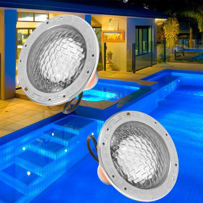 Two Pentair 78456300 White Amerlite Incandescent Lights, each with a 120V 500W power capacity and a 100' cord, are displayed against a backdrop of a brightly lit pool and modern house at night. The stainless steel finish of these Pentair Pool lights complements the contemporary design, enhancing the poolscape with an elegant glow.