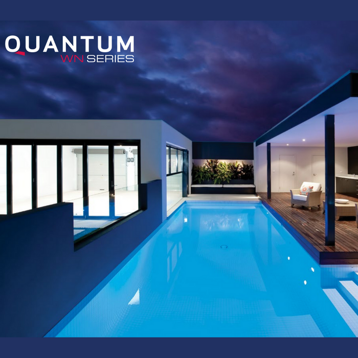 Modern house with a lit swimming pool at night, featuring an outdoor seating area and large glass windows. The Spa Electrics QUANTUM WN Series 6" LED Pool Lights Q6 ensures a mesmerizing glow from the underwater high-intensity ceramic light engine. "Quantum WN Series" text.