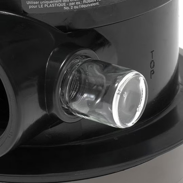 Close-up of a clear cylindrical glass component attached to a black plastic appliance, labeled "TOP" with the Hayward SP071621 Multiport Vari-Flo Control 2" FIP Valve Top Mount for Sand Filters from Hayward.